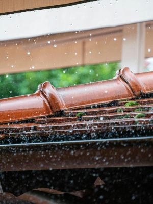 Detailed view of rain droplets cascading off a terracotta roof, capturing the essence of a rainy day.